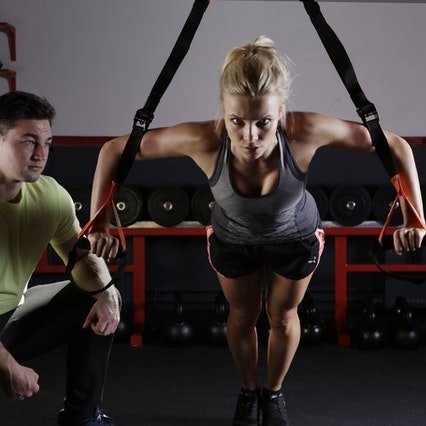 woman exercising with trainer's supervision